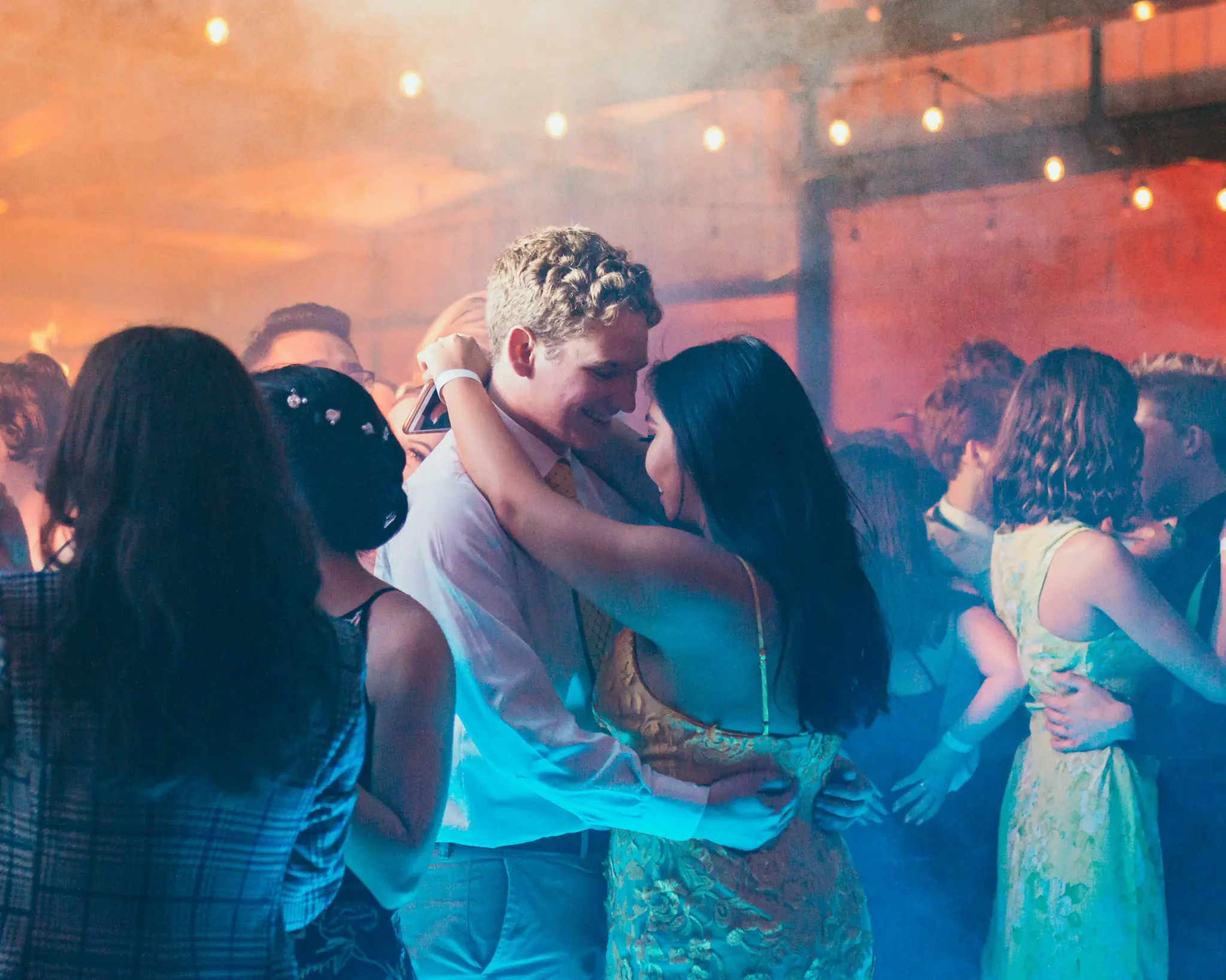 Photo of a couple dancing at prom among the guests.