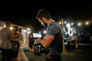 Photo of a wedding videographer filming a wedding in the evening.