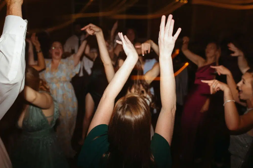 Photo of people dancing with their hands up at a party for entertainment ideas for corporate events.