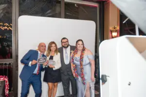 Photo of two women and two men taking pictures at a photo booth while holding fun signs.