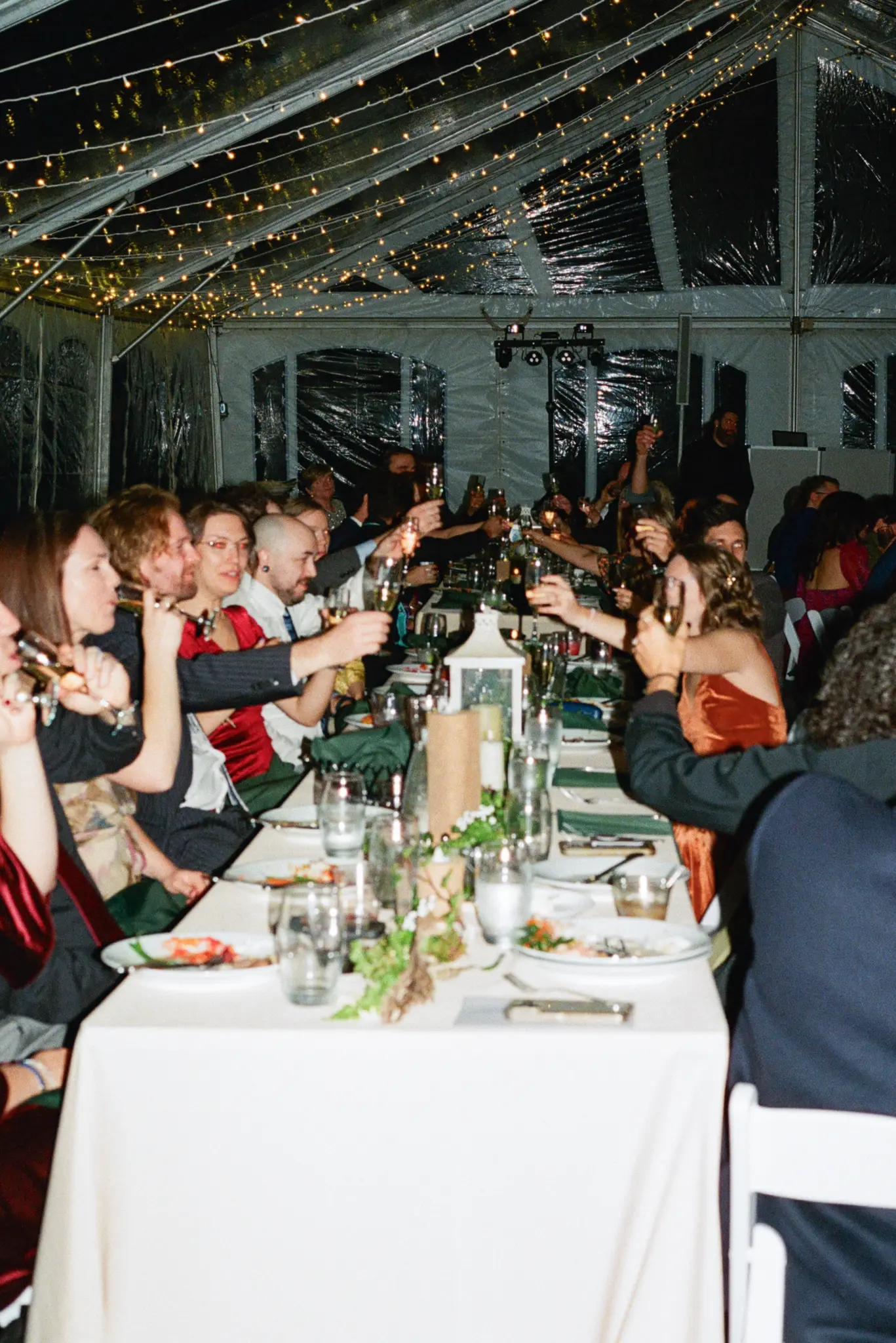 Photo of wedding guests having dinner at a long table.