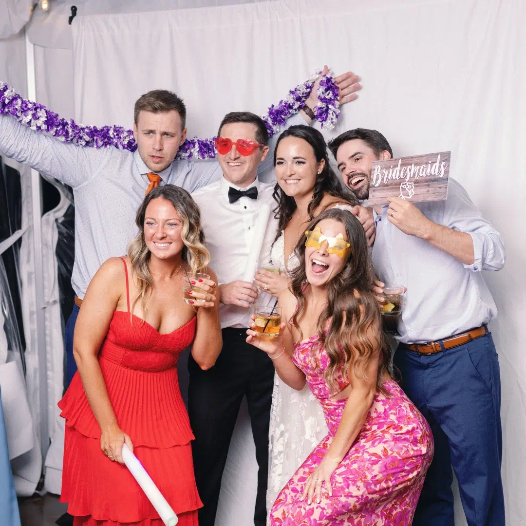 Photo of wedding guests taking pictures at a backdrop with fun signs and accessories.