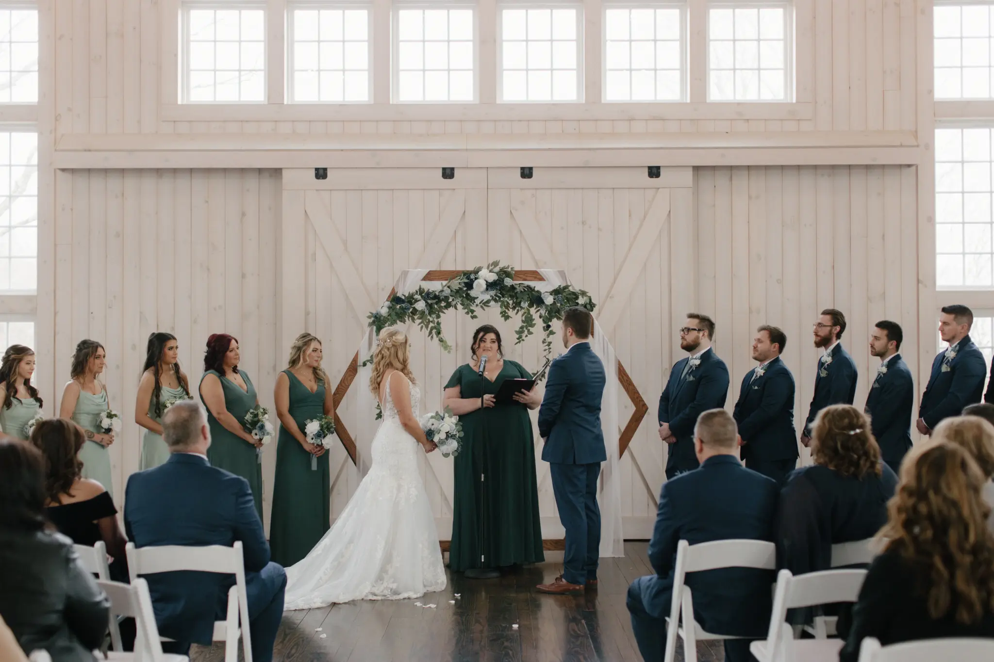 Photo of a couple getting their wedding officiated while surrounded by the bridesmaids and groomsmen and seated guests.