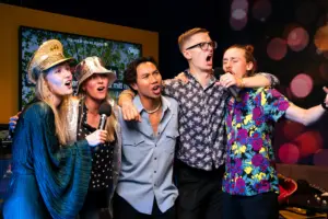 photo-of-a-group-of-friends-wearing-fun-hats-and-singing-karaoke