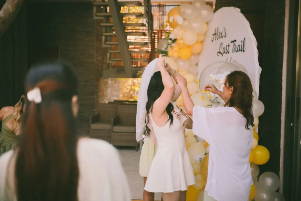 photo of a bride wearing a bride to be tag and putting on her veil at a wedding shower