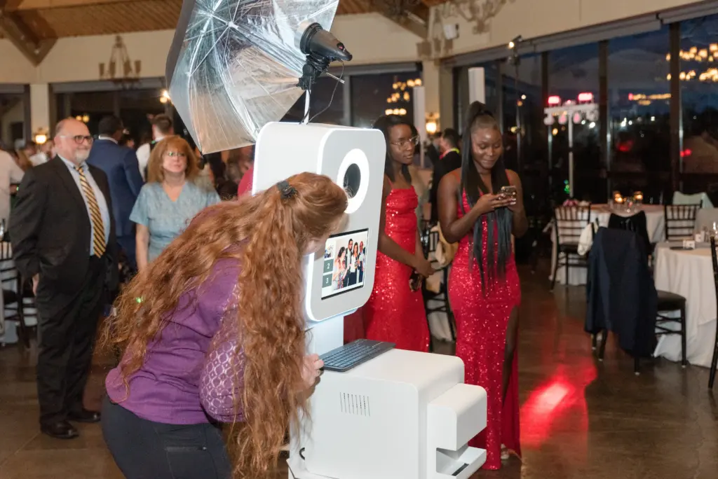 photo of a woman operating a photo booth with guests waiting in line for how much is a photo booth rental