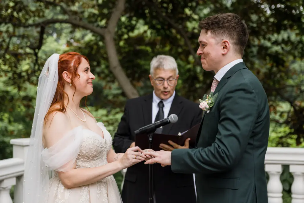 photo-of-a-bride-and-groom-holding-each-others-hands-while-facing-each-other-as-the-officiant-reads-into-the-mic