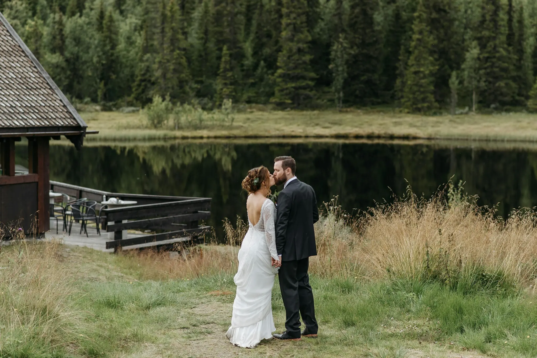 photo of a bride and groom kissing in a forest in front of a lake