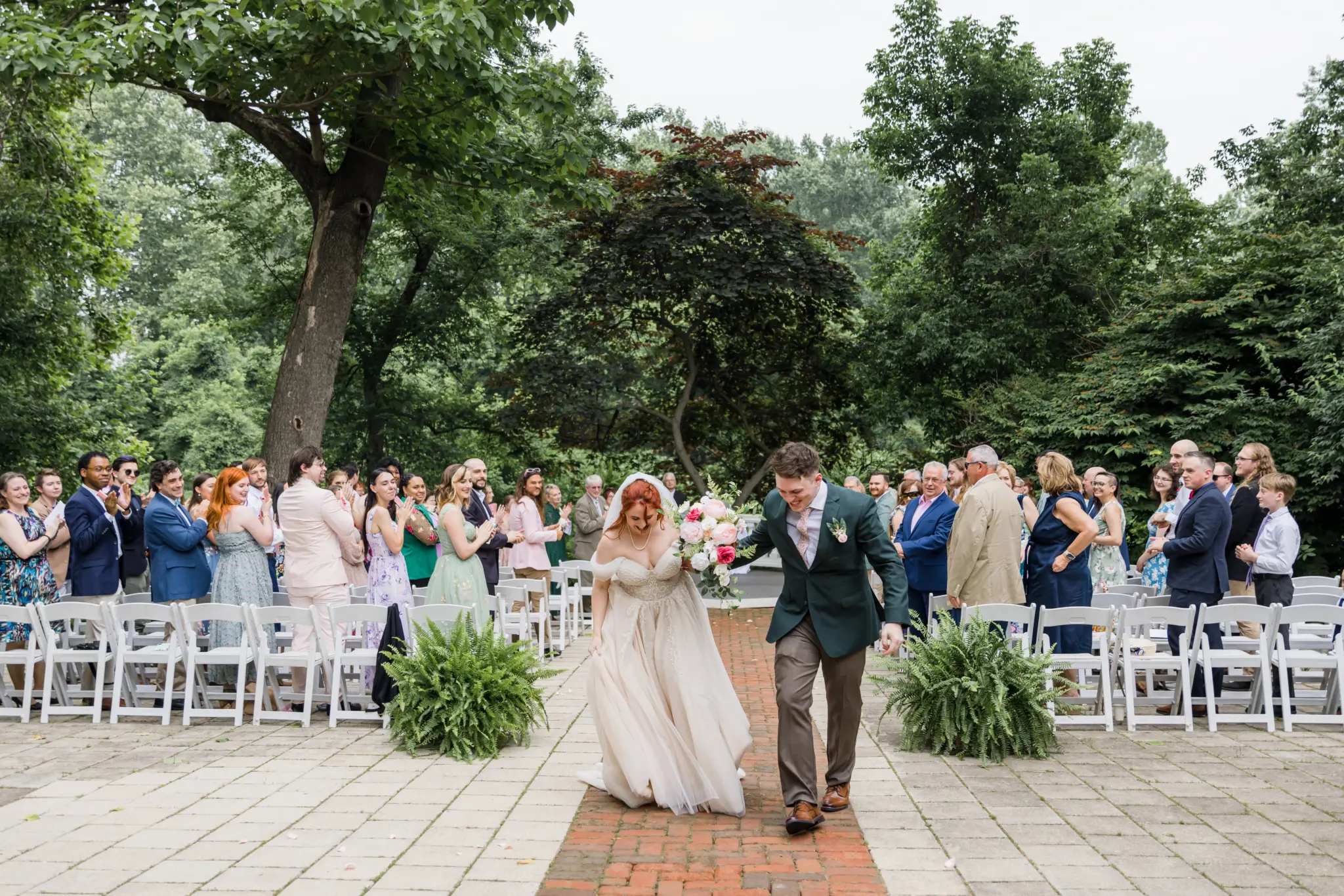 photo-of-a-bride-and-groom-walking-down-the-aisle-at-an-outdoors-forest-venue-for-what-is-a-wedding-rehearsal