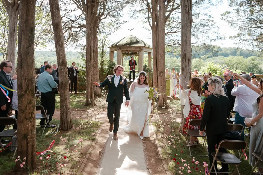 photo-of-a-bride-and-groom-walking-down-the-aisle-in-a-forest-venue-for-wedding-party-entrance-ideas