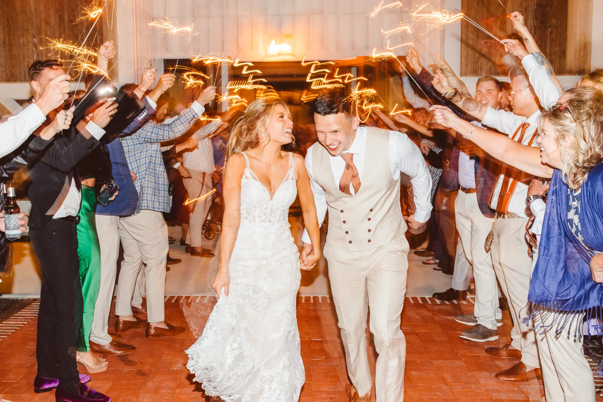 photo-of-a-couple-entering-their-reception-venue-while-their-guests-hold-out-sparklers
