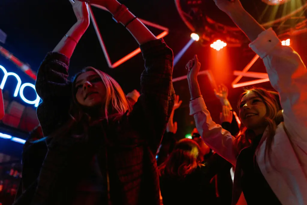 photo of two girls dancing with their arms up at a party for corporate party ideas