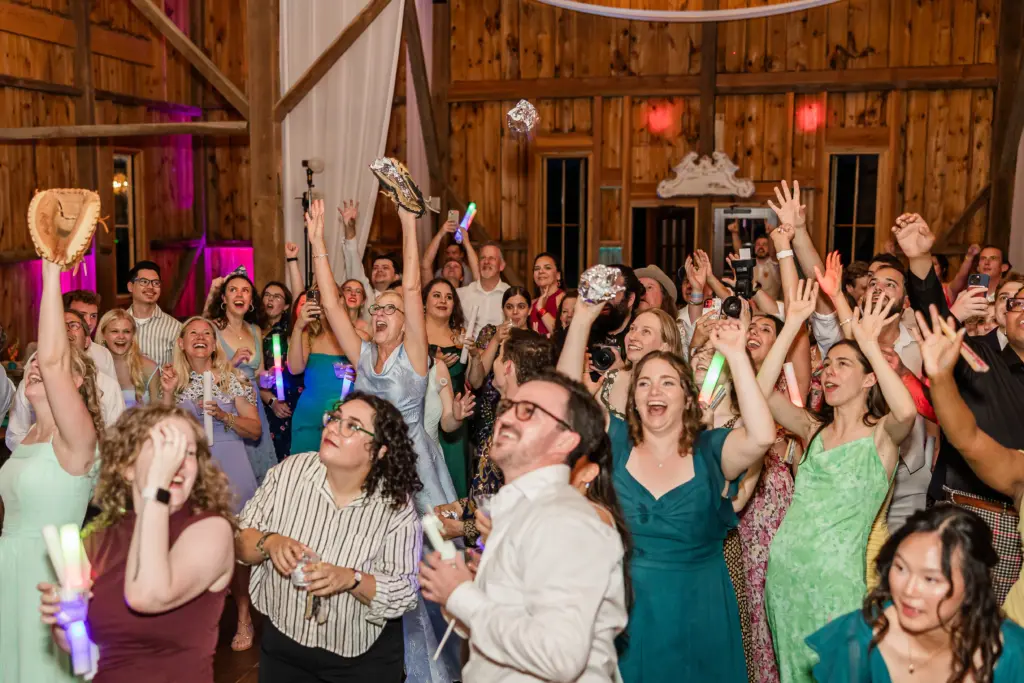 photo of wedding guests gathered for a photo and raising their hands for dj columbia