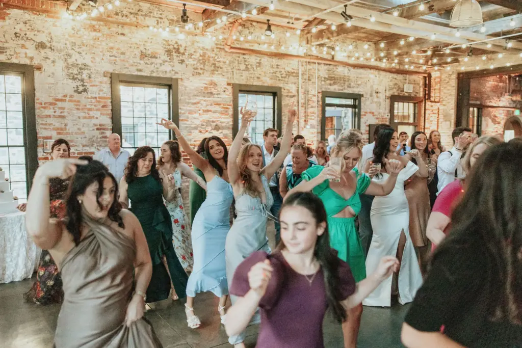 photo guests dancing with hands up at rustic mill wedding reception