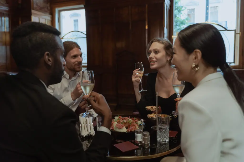 photo-of-two-men-and-two-women-at-a-dinner-table-talking-with-drinks-in-their-hands