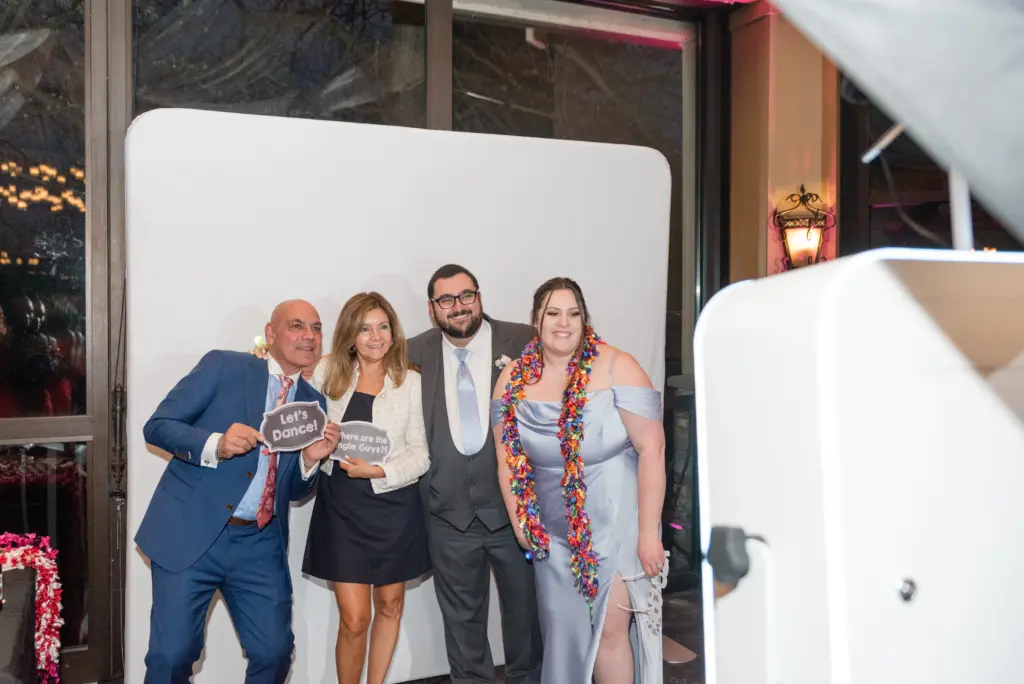 photo-of-two-women-and-two-men-taking-pictures-at-a-photo-booth-while-holding-fun-signs