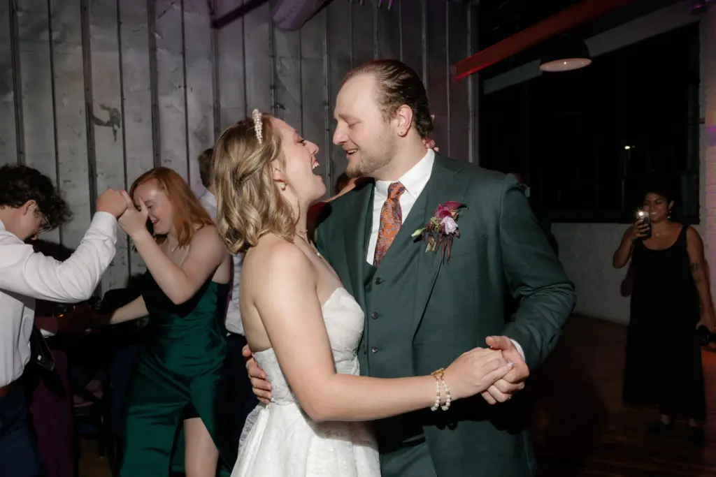photo of a bride and groom laughing while dancing together