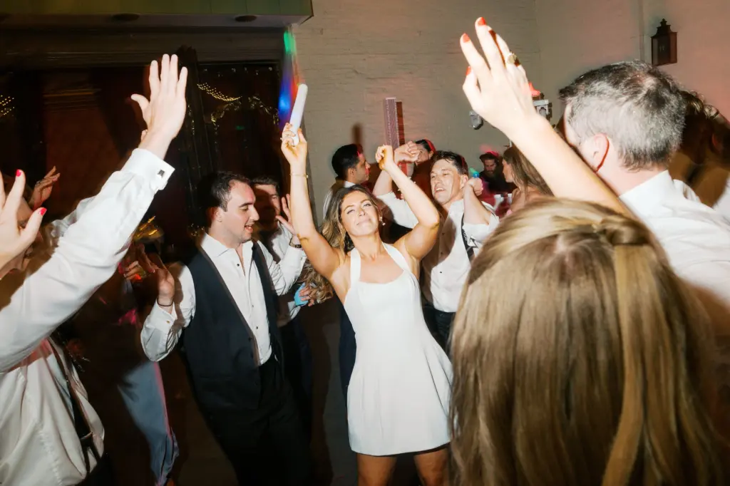 photo of a bride dancing with her guests with a glowstick in her hand