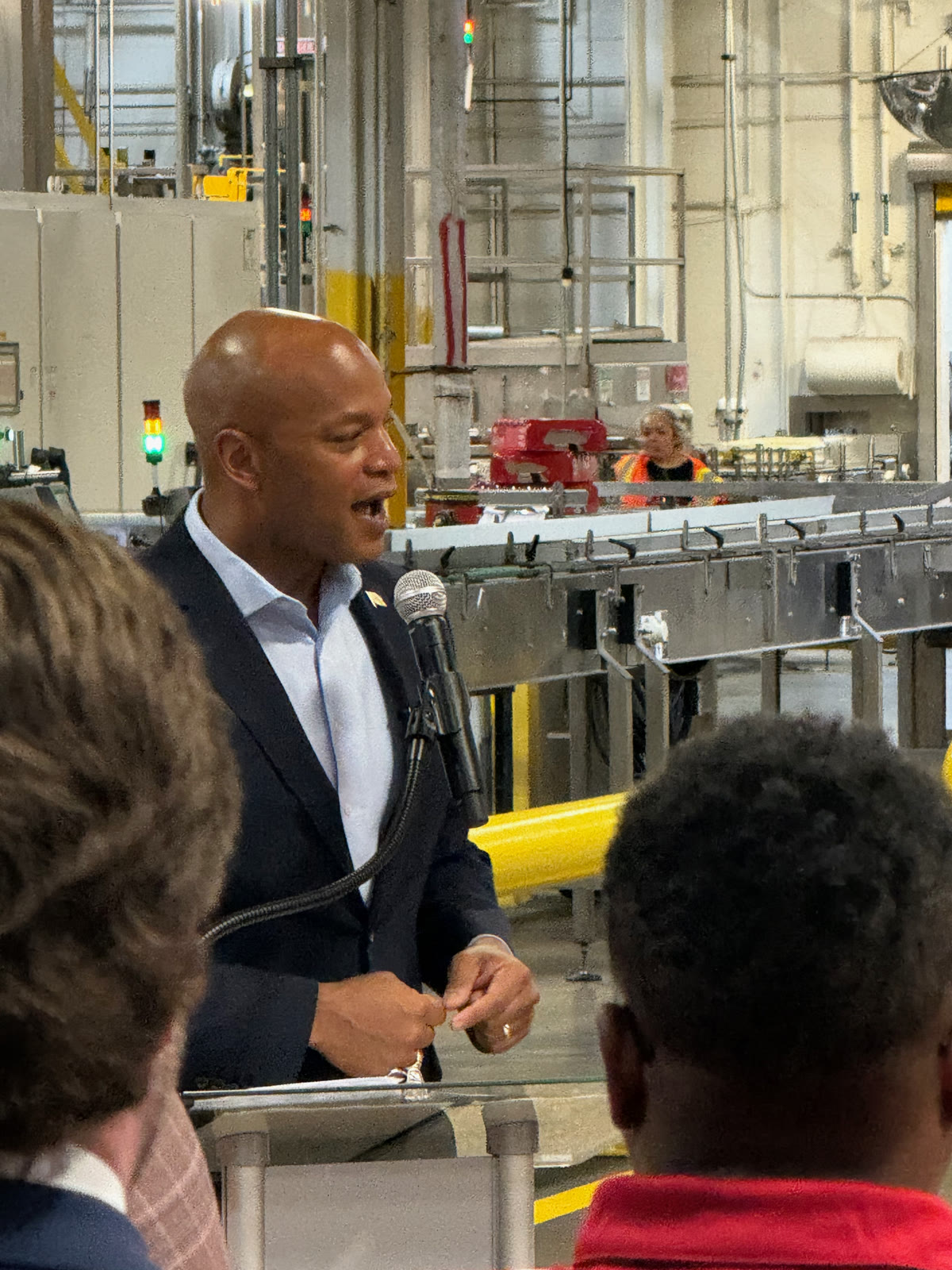 Maryland Governor Wes Moore speaking at the podium inside the Coca-Cola Baltimore plant