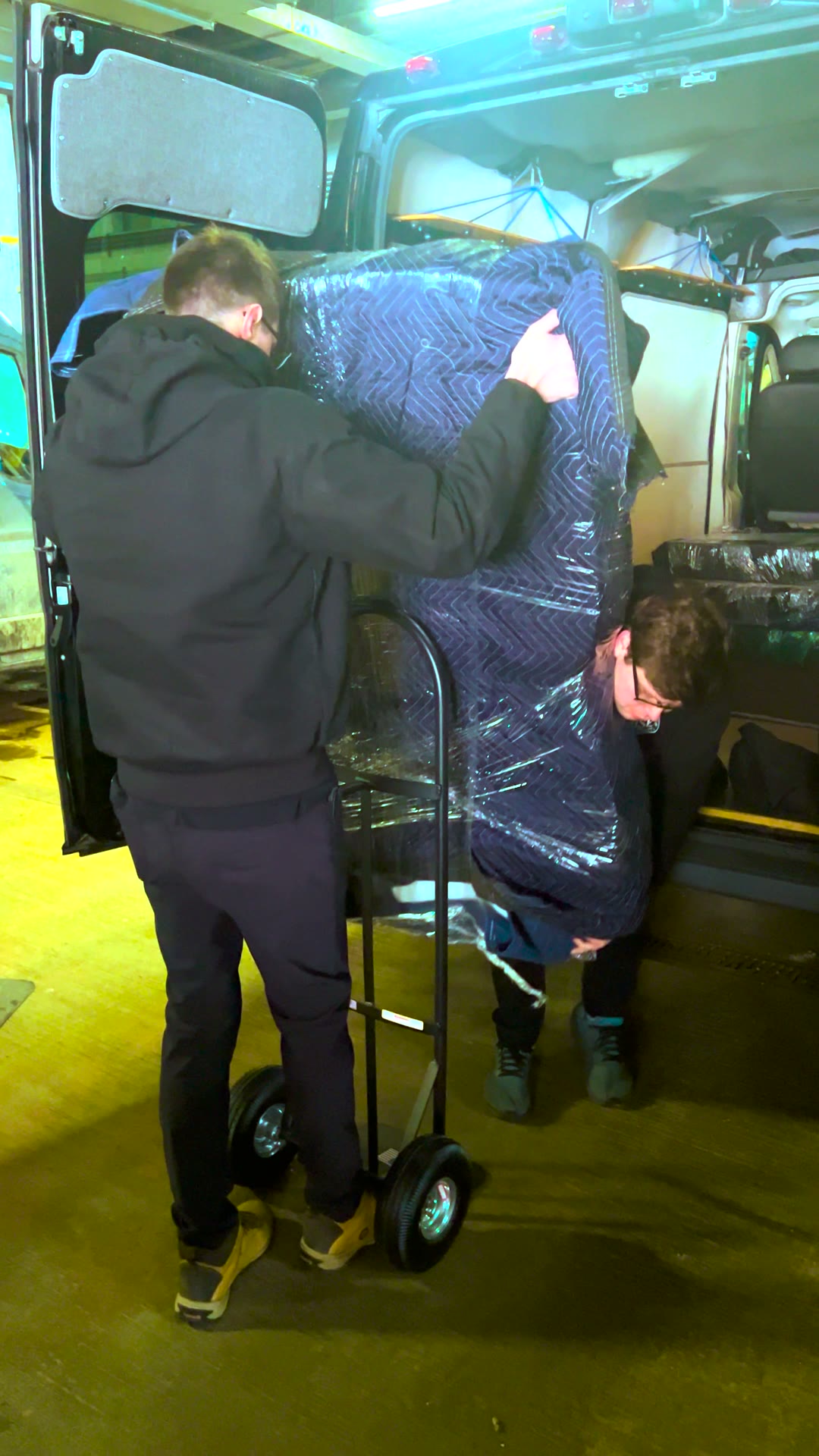 BSE crew wheeling a padded marquee letter out of the van on a hand truck