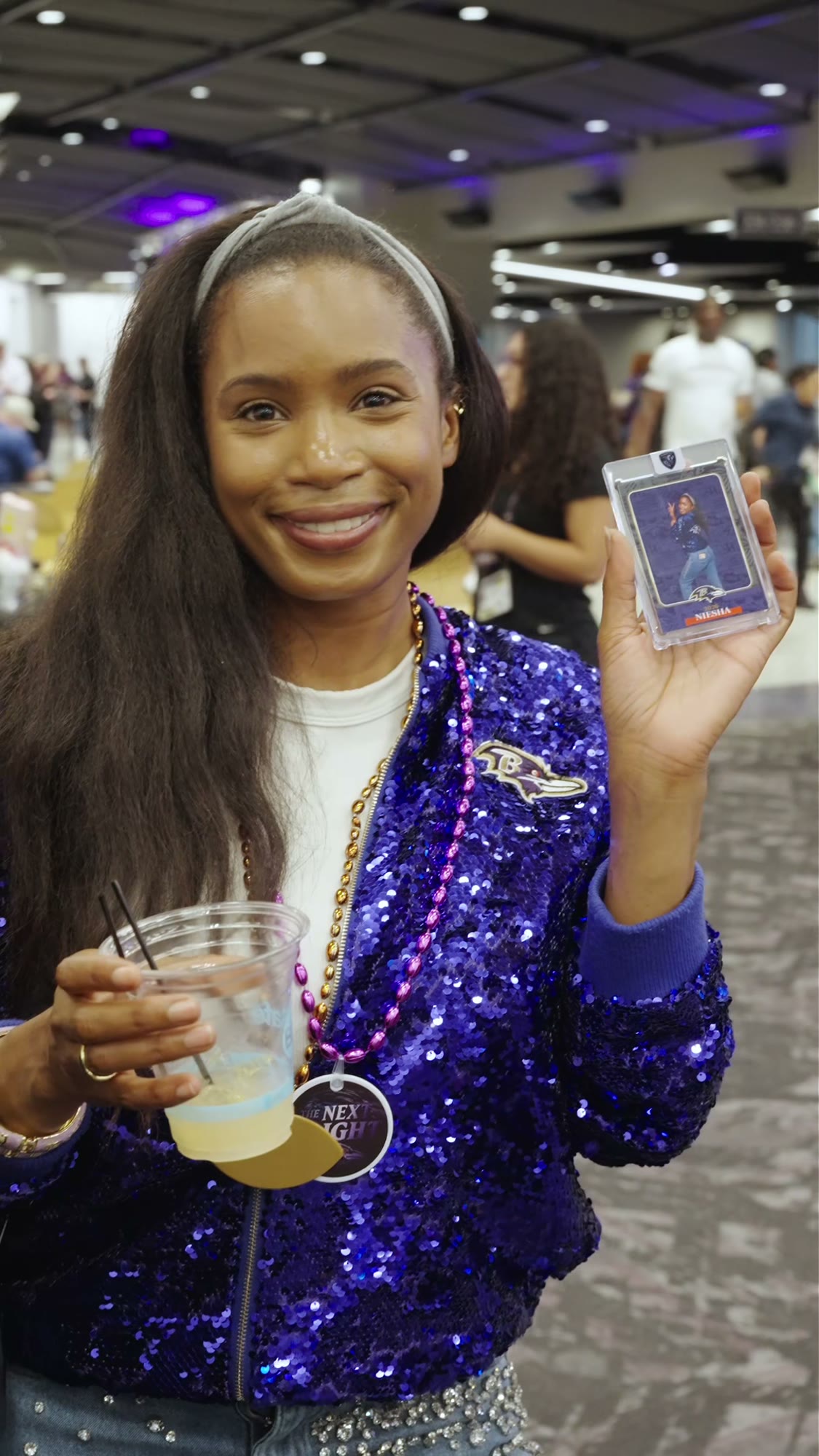 A smiling fan holding a custom football trading card at the Ravens Draft Party